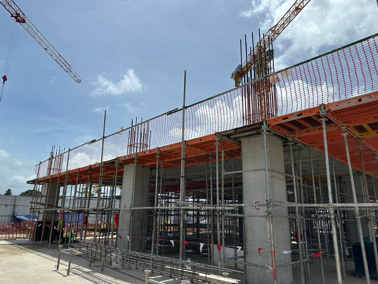 Finished concrete columns supporting orange slab formwork tables