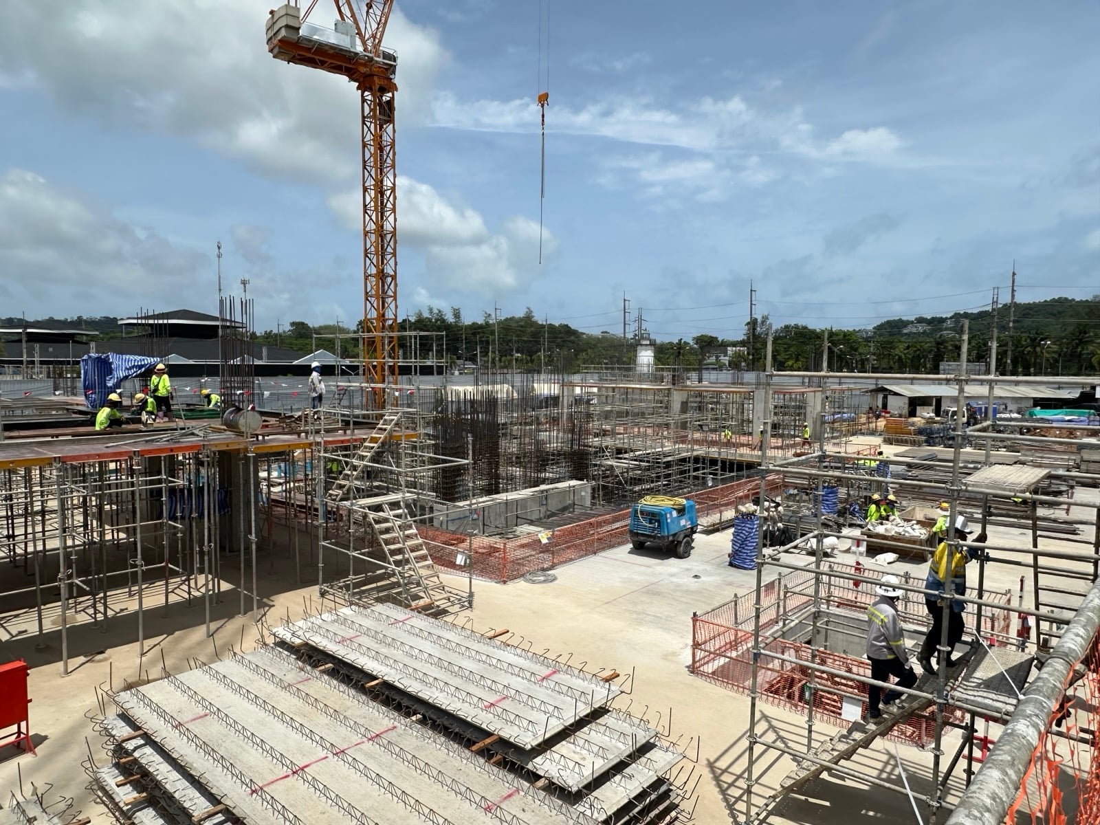 Wide site view with a tower crane and scaffolding across multiple structures